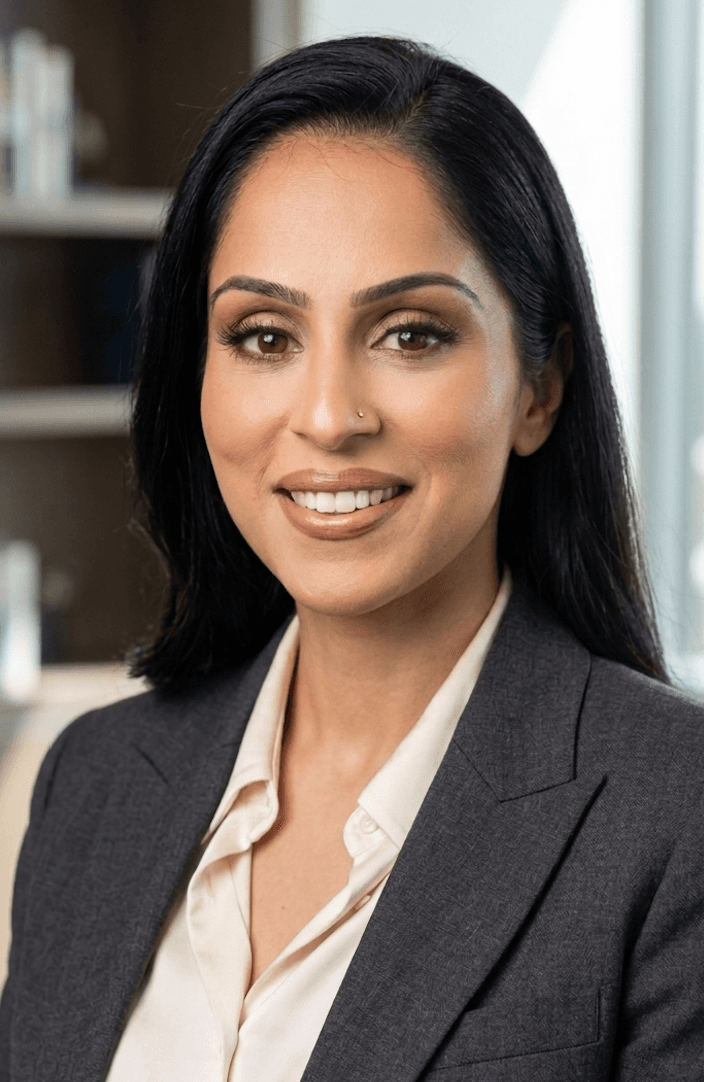 Smiling woman with long dark hair and nose stud wearing a professional charcoal grey blazer.